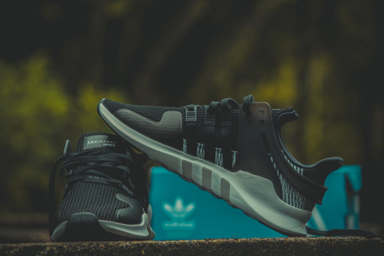 Modern black Adidas sneakers showcased with a distinctive blue box outdoors.